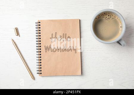 Inizi la sua settimana con buon umore. Notebook con testo Ciao Lunedi, tazza di caffè e penna su tavolo di legno bianco, piatto Foto Stock