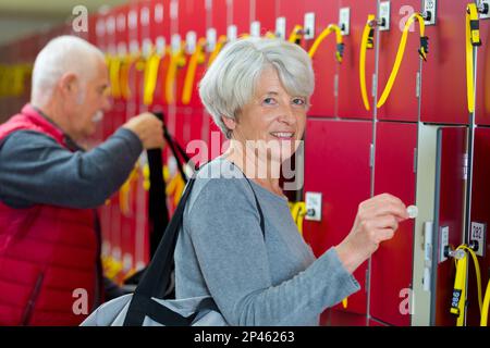 ritratto di donna anziana che mette moneta in armadietto Foto Stock