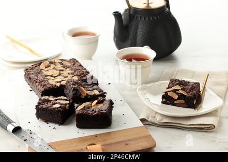 Brownie al cioccolato Fudgy fatte in casa su sfondo bianco tavolo, servito con tè. Torta al cioccolato Almond Brownie Still Life Foto Stock