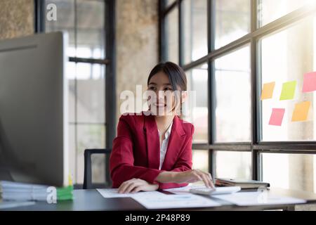 donna d'affari che lavora in ufficio con l'uso di una calcolatrice per calcolare i numeri, concetto di contabilità finanziaria Foto Stock