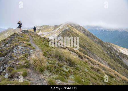 Due escursionisti che camminano lungo un sentiero escursionistico in cima a una cresta di montagna nel Nelson Lakes National Park di Aotearoa, Nuova Zelanda. Foto Stock