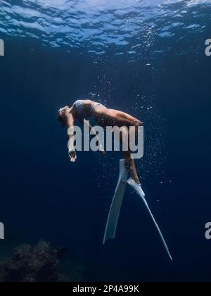 Donna freediver scivola sott'acqua con bolle d'aria. Immersioni in mare con ragazza Foto Stock