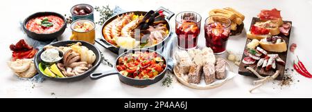 Tipico concetto di tapas spagnole. Il concetto include jamon, salsiccia di chorizo, brushette, ciotola con olive, gamberi, padella con paella, formaggio, sangria, churros Foto Stock