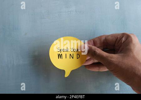 Vista dall'alto immagine della mano che tiene la bolla del discorso con il testo parla la TUA MENTE. Concetto di virgolette motivazionali Foto Stock