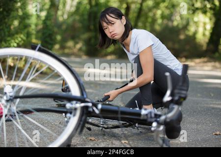 donna infastidita che tira su una gomma della bici Foto Stock