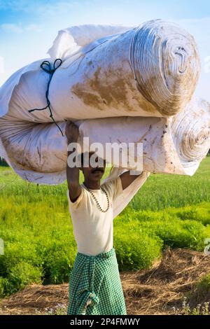 Uomo nepalese del gruppo etnico di Tharu che porta in testa un grande rotolo di fazzoletti, Chitwan, Nepal Foto Stock