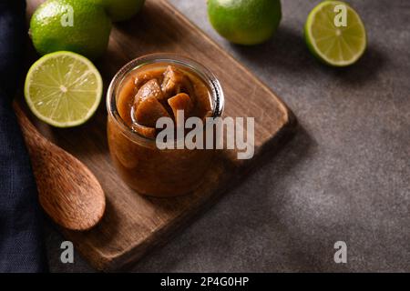 Pickle di lime dello Sri Lanka fatto in casa di lime, sale, peperoncino, pepe su fondo marrone. Vista dall'alto. Spazio di copia. Primo piano. Foto Stock