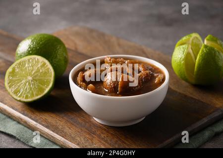 Tradizionale filone di lime dello Sri Lanka, sale, peperoncino, pepe su fondo marrone. Primo piano. Foto Stock