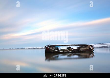 Naufragio innevato di vecchia chiatta nel fiume di marea al tramonto, Fremington Quay, River Taw, vicino Barnstaple, North Devon, Inghilterra, Regno Unito Foto Stock