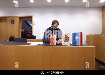 Augusta, Germania. 06th Mar, 2023. Un uomo di 34 anni siede nel molo del tribunale distrettuale, dietro libri sul cambiamento climatico. L'uomo è accusato di aver occupato il governo di Swabia con altre due persone nell'ottobre 2022, nonostante un divieto di casa, e di aver accusato l'allora presidente di governo di corruzione. Credit: Karl-Josef Hildenbrand/dpa/Alamy Live News Foto Stock