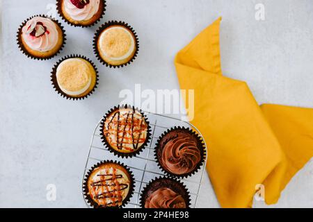 Deliziosi cupcake su griglia di raffreddamento con tovagliolo giallo Foto Stock