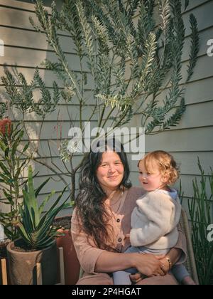 Madre e figlia circondata da piante sul portico anteriore Foto Stock