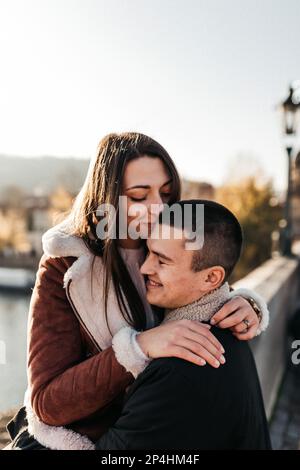 donna felice abbracciò suo marito contro il fiume in autunno Foto Stock