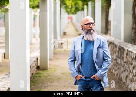 uomo che si posa in piedi con le mani in tasca in un parco cittadino. Foto Stock