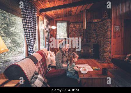 Madre e figlia fanno colazione in una cabina forestale Foto Stock