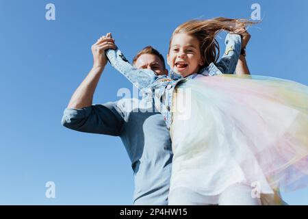 Padre solleva figlia in aria Foto Stock