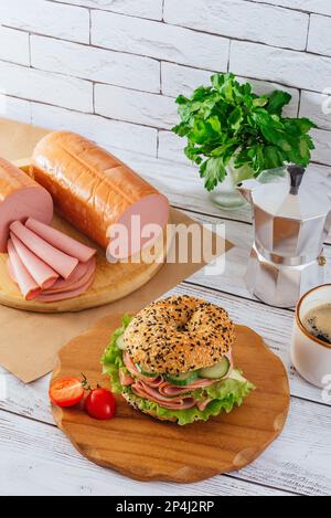 bagel con prosciutto ed erbe aromatiche. il prosciutto è nelle vicinanze. caffè. prima colazione. Foto Stock