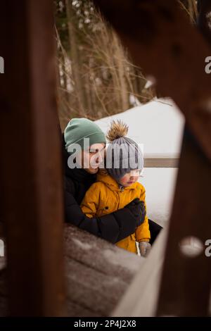 Papà e figlio che guardano qualcosa nella foresta invernale Foto Stock