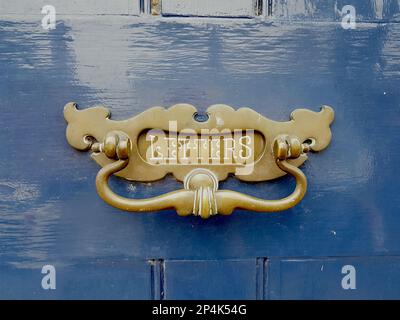Particolare di una scatola di lettere in ottone su una porta blu scuro. Foto Stock