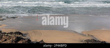 Un'immagine panoramica della piccola figura di persona che corre lungo la costa su una ventosa Fistral Beach a Newquay in Cornovaglia. Foto Stock