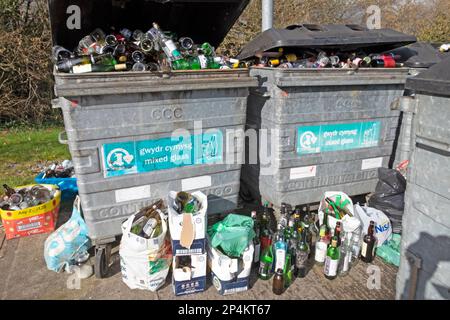 Bottiglie di vetro in contenitori a bidoni e al suolo presso la stazione di riciclaggio delle bottiglie nel Carmarthenshire Wales UK 2023. KATHY DEWITT Foto Stock