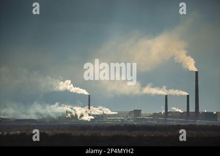 Inquinamento atmosferico da camini di centrali elettriche. Fabbrica di pasta di legno e mulino Foto Stock