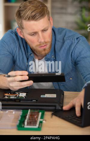 uomo che fissa la scheda a circuito stampato nel computer portatile utilizzando un cacciavite Foto Stock