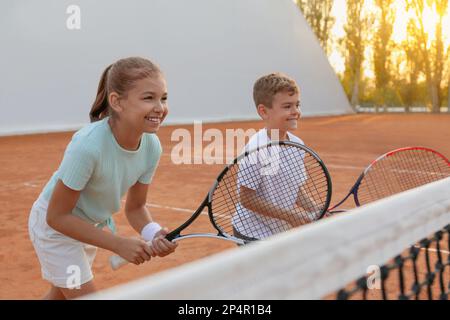Felici i bambini che giocano a tennis sul campo all'aperto Foto Stock