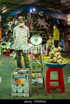 Un uomo si ferma a guardare alcune piante e verdure da una serie di scale nel mercato centrale, Phnon Penh, Cambogia. Foto Stock