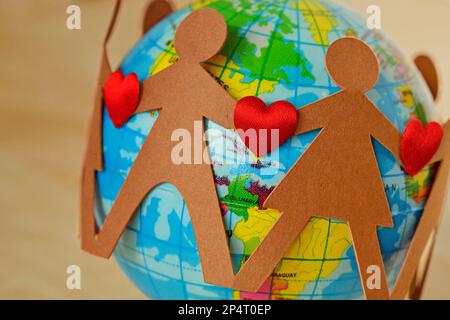 Carta persone con il cuore in un cerchio intorno al globo della terra - concetto di amore per il pianeta e questioni ambientali Foto Stock