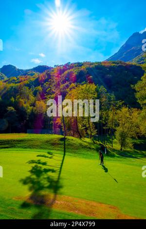 Golfista mettere sul campo da golf Menaggio con Mountain View in autunno in Lombardia. Foto Stock