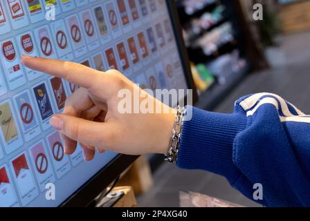 Monaco, Germania. 06th Mar, 2023. Una donna tocca il dito sul display di un distributore automatico di sigarette in un supermercato alla cassa. Credit: Sven Hoppe/dpa/Alamy Live News Foto Stock