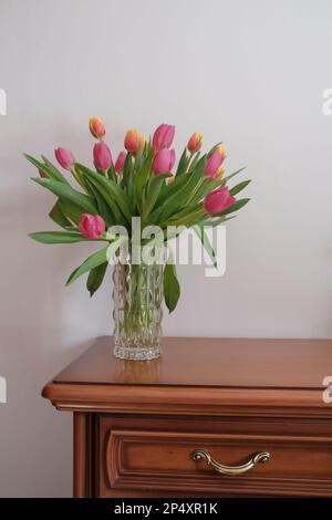 bouquet di tulipani rosa e giallo in vaso closeup su bianco tutto sul cassetto di legno. Dettagli interni. Interno dell'hotel Foto Stock