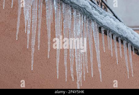 Ghiaccioli sul tetto. Lo scarico è pieno di neve e ghiaccio. Ghiaccio cadere concetto di pericolo. Foto Stock