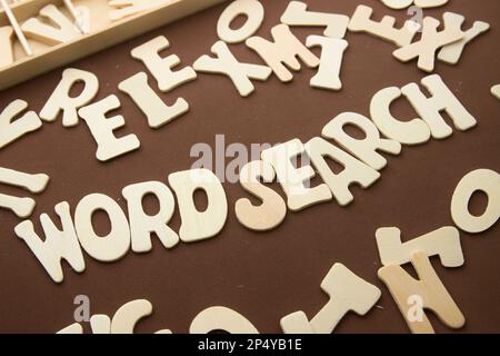 Immagine di alcune lettere di legno allineate su uno sfondo marrone in cui 'Ricerca per parole' è letta in inglese insieme ad altre lettere disordinate Foto Stock