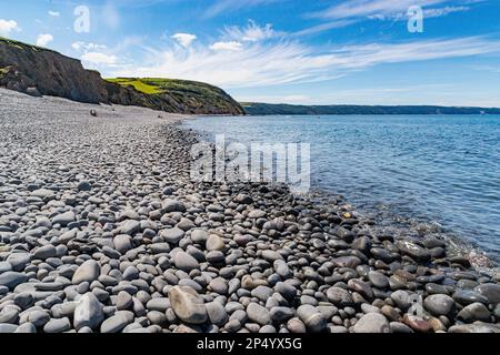 Greencliff Pebble Beach e Sea View verso Hartland Point a High Tide con Blue Sky. Questi ciottoli si estendono lungo la costa. Vicino Bideford, Devon, Foto Stock