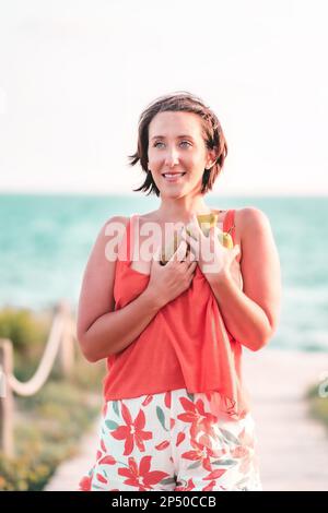 Una giovane donna che tiene felicemente le pere nel parco il giorno di estate. Concetto di stile di vita sano Foto Stock