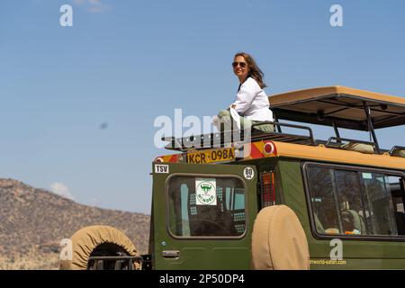 Giovane ragazza turistica seduta sul tetto di una nave da crociera durante il safari e guardando la fauna selvatica di samburu in kenya Foto Stock