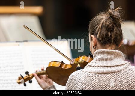 Orchestra sinfonica professionale che suona sul palco e suona un concerto di musica classica, violinista in primo piano Foto Stock