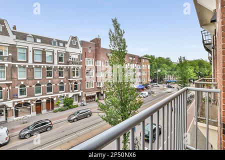 Amsterdam, Paesi Bassi - 10 aprile, 2021: Un balcone con auto parcheggiate sulla strada e gli edifici sullo sfondo, amsterdam, paesi bassi - stockfoorent com Foto Stock