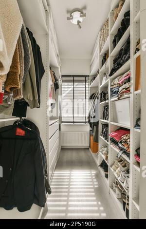 Amsterdam, Paesi Bassi - 10 aprile, 2021: Una passeggiata - in armadio con un sacco di vestiti appesi alla parete, e scaffali che reggono vari tipi di abbigliamento Foto Stock