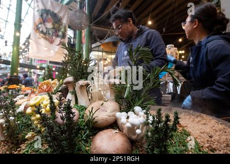 Stand gastronomico a Borough Market, Londra UK, che vende risotti di funghi selvatici da take away preparati al momento con farro. Funghi selvatici in primo piano. Foto Stock