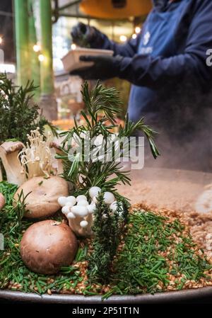 Stand gastronomico a Borough Market, Londra UK, che vende risotti di funghi selvatici da take away preparati al momento con farro. Funghi selvatici in primo piano. Foto Stock