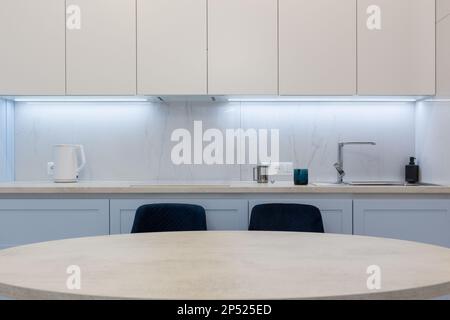 Tavolo da pranzo all'interno della cucina moderna. Tavolo da cucina rotondo e due sedie in interni moderni. Foto Stock