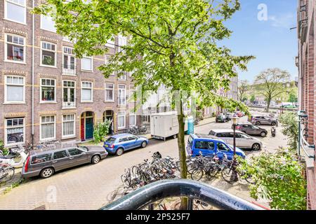 Amsterdam, Paesi Bassi - 10 Aprile, 2021: Una strada urbana con auto e biciclette parcheggiate sul marciapiede di amsterdam, paesi bassi foto d'archivio - 1118793 Foto Stock