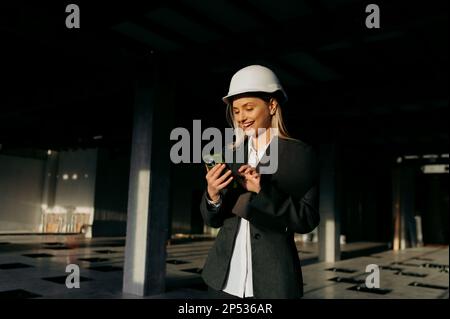 Giovane architetto donna sorridente felice utilizzando lo smartphone in ufficio. Foto Stock