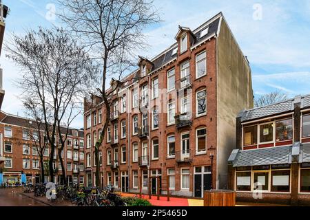 Amsterdam, Paesi Bassi - 10 aprile, 2021: Una strada cittadina con biciclette parcheggiate sui marciapiedi e gli edifici sullo sfondo, tutte salite su un lato Foto Stock