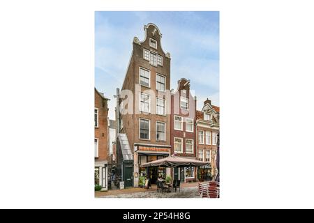 Amsterdam, Paesi Bassi - 10 aprile, 2021: Un vecchio edificio con un orologio sul lato e persone che camminano per la strada accanto agli altri edifici Foto Stock