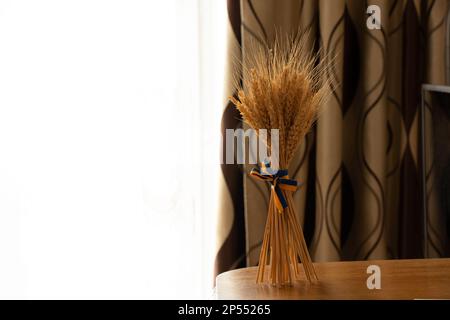 Spikelets di grano, legato con un nastro del colore della bandiera Ucraina, in piedi sul tavolo nella Casa Ucraina, la bandiera dell'Ucraina, fermare la wa Foto Stock