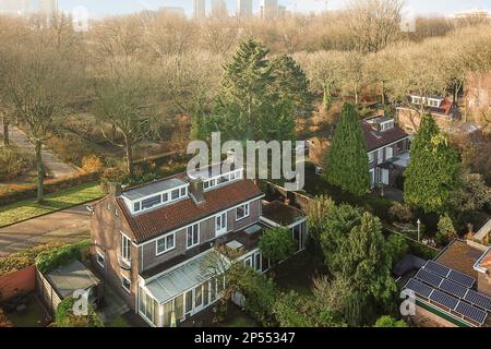 Amsterdam, Paesi Bassi - 10 aprile 2021: Vista aerea di alcune case della città con alberi ed edifici su entrambi i lati della strada, come visto dall'alto Foto Stock